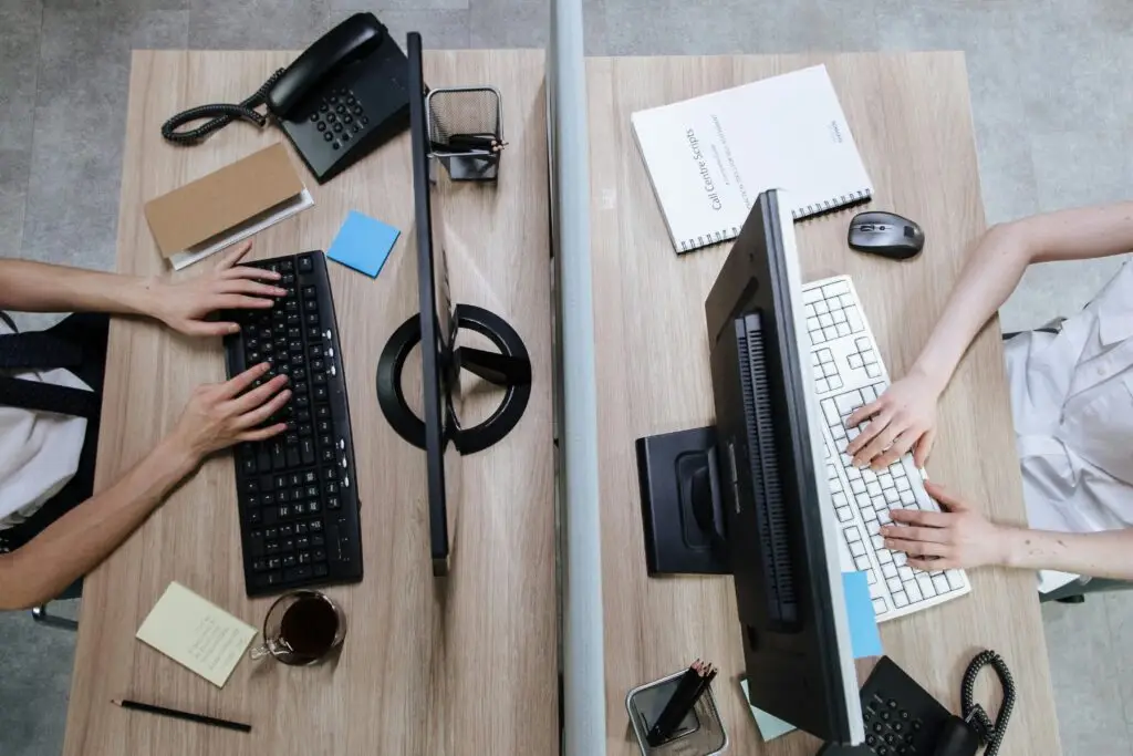 Top view of two workstations with people typing on keyboards, during the day in an office setting.